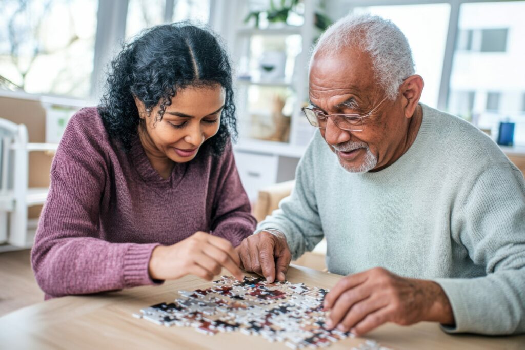 An elderly man and a female caretaker building a puzzle together